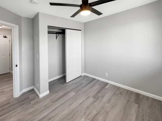 an empty room with wooden floor and a ceiling fan
