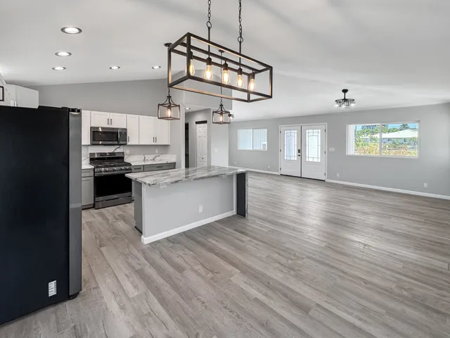 a kitchen with stainless steel appliances granite countertop a refrigerator a stove top oven a sink and dishwasher