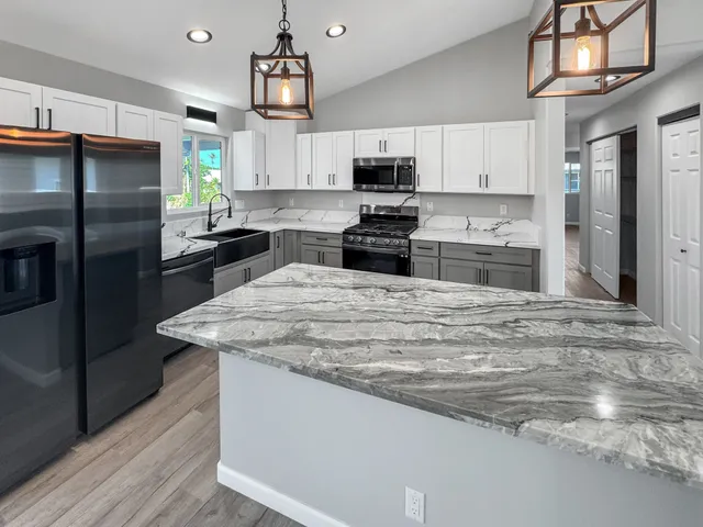 a kitchen with stainless steel appliances granite countertop a sink a stove and refrigerator