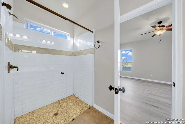 a view of a hallway with wooden floor and a bathroom