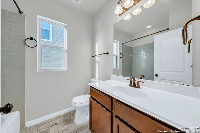 a bathroom with a sink a toilet a mirror and shower