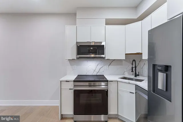 a kitchen with stainless steel appliances granite countertop white cabinets and a stove top oven