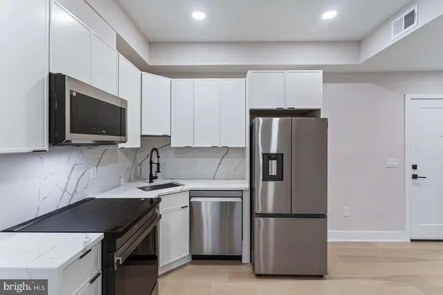 a kitchen with stainless steel appliances granite countertop a refrigerator stove a sink and a microwave