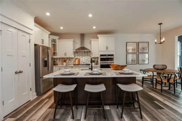 a kitchen with stainless steel appliances a dining table chairs and a refrigerator