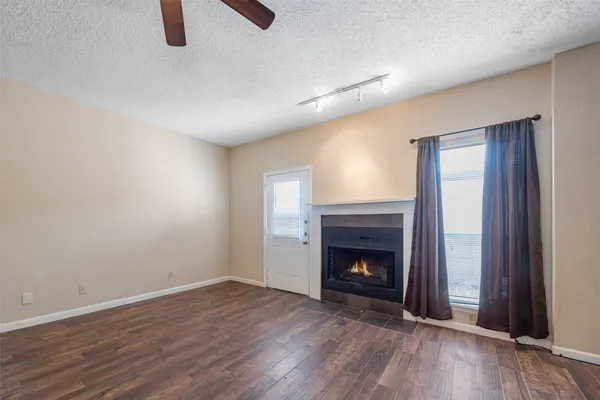 a view of an empty room with wooden floor fireplace and a window