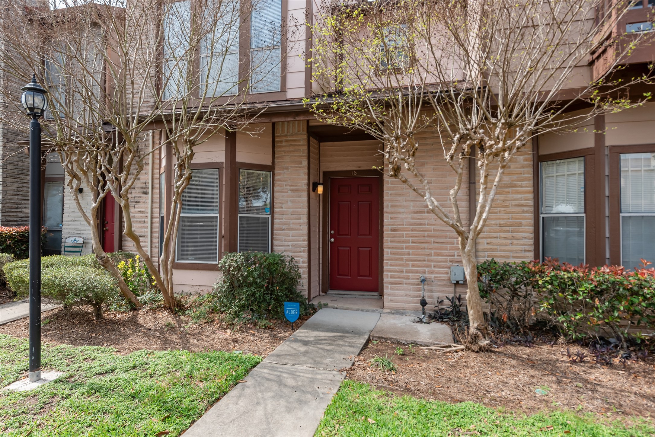 12400 Brookglade Circle, Unit 15 Houston, TX 77099 - Photo 2 of 43 a view of a brick house with many windows plants and large tree