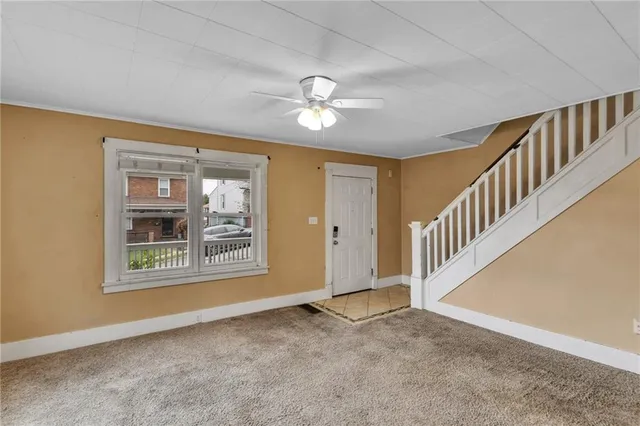a view of an empty room with chandelier fan