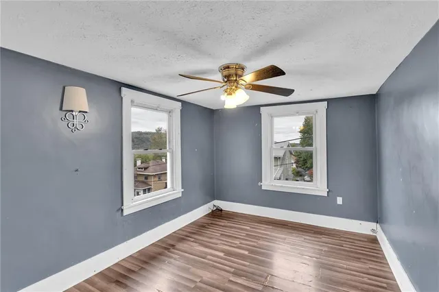 a view of an empty room with window and wooden floor