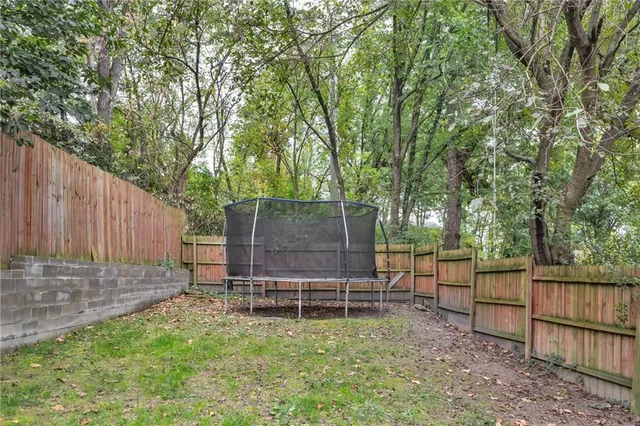 a view of a backyard with wooden fence and a large tree