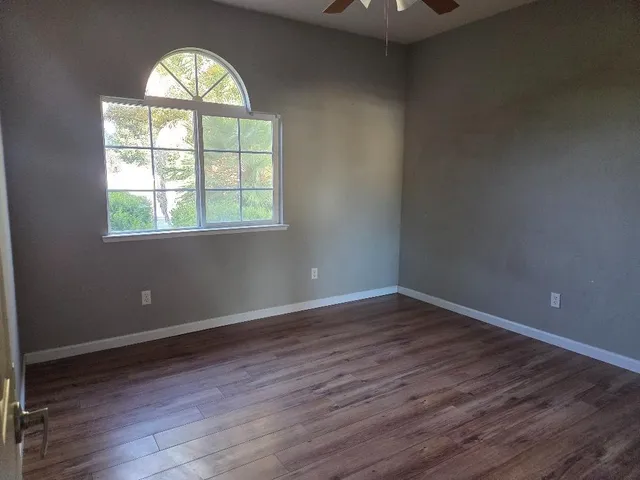 an empty room with wooden floor windows and chandelier