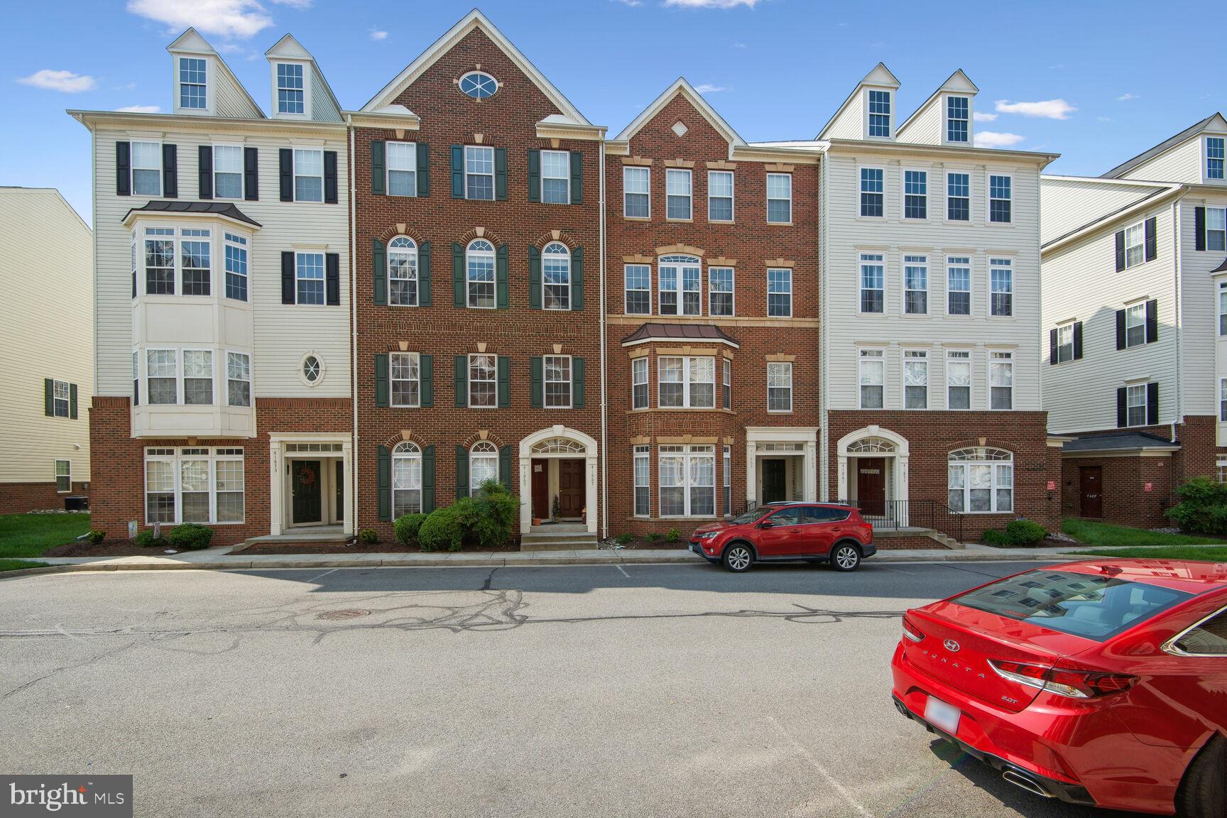 a front view of a residential apartment building with cars parked