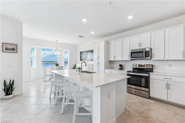 a kitchen with stainless steel appliances granite countertop a stove top oven a sink a dining table and chairs