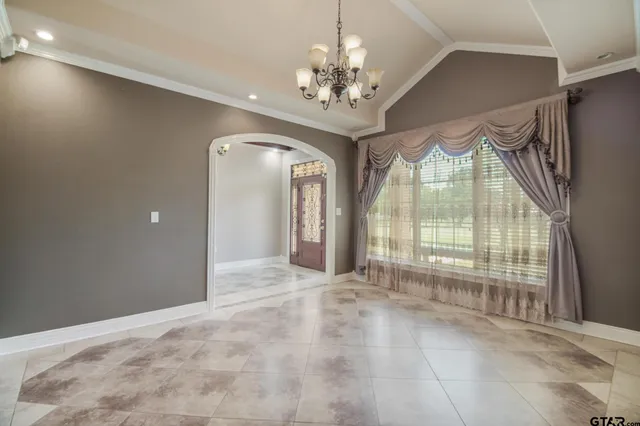 a view of an empty room with a fireplace and a chandelier fan