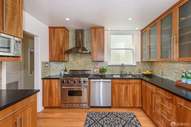 a kitchen with stainless steel appliances granite countertop a stove a sink and a microwave