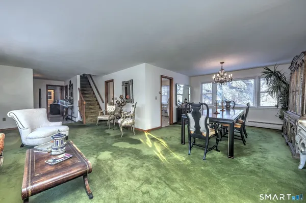 a living room with furniture and a dining table with rug floor