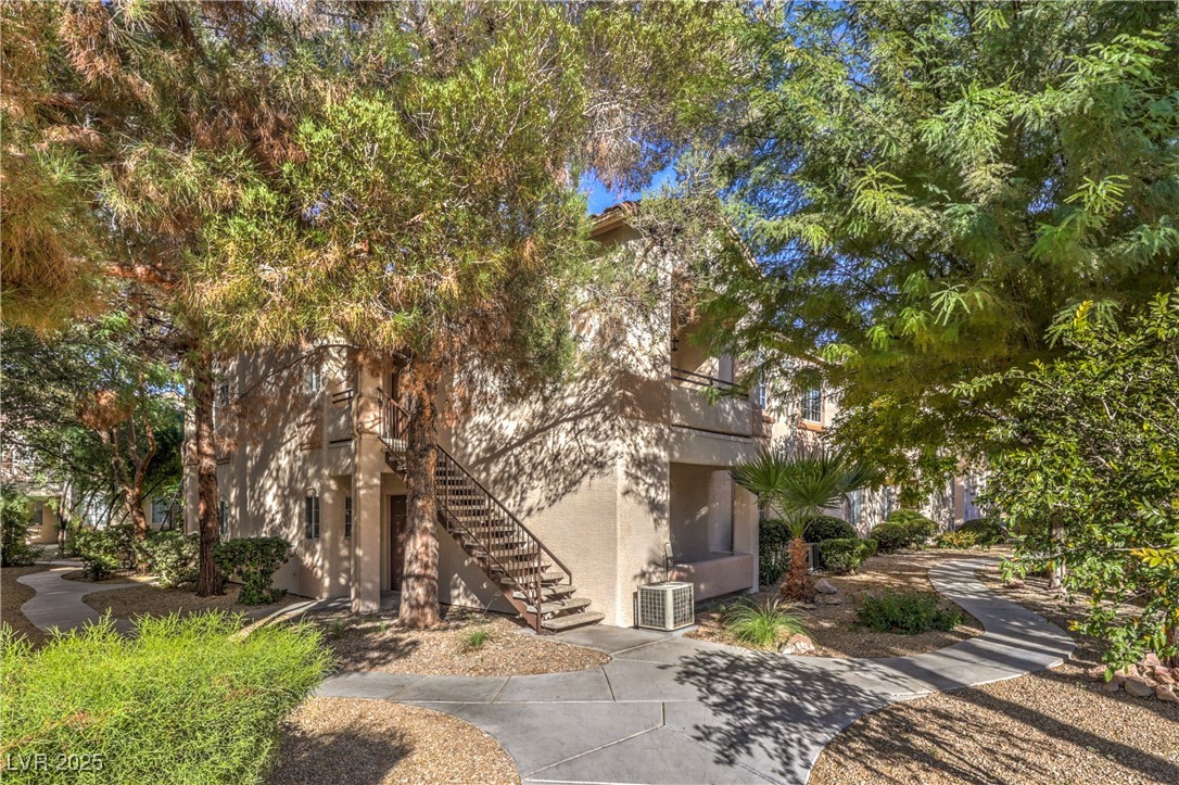 View of front facade featuring a balcony, stucco siding, and stairs