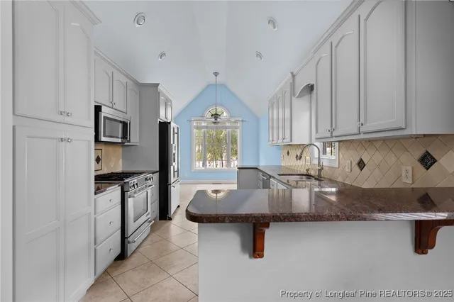 a kitchen with granite countertop a sink a stove and refrigerator
