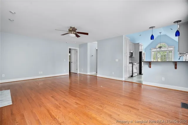 a view of an empty room with kitchen and a window