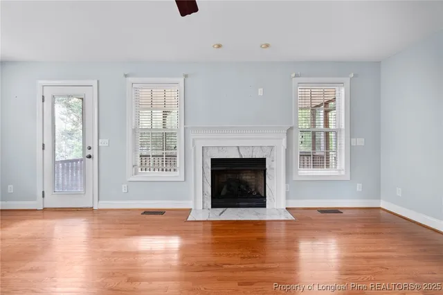 a view of a livingroom with wooden floor a fireplace and windows