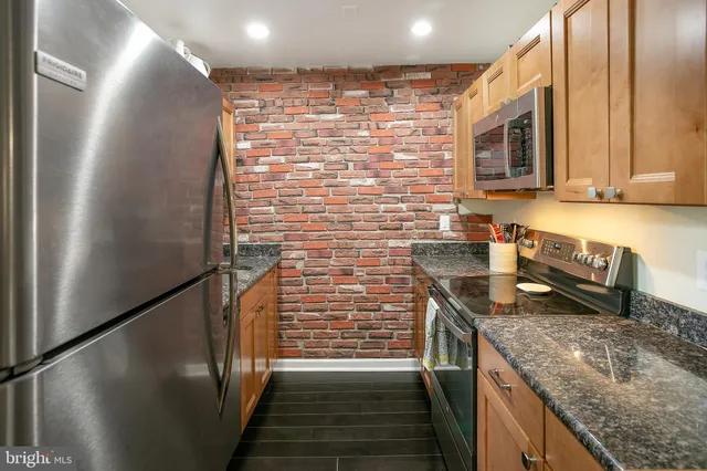 a kitchen with stainless steel appliances granite countertop a sink and a refrigerator