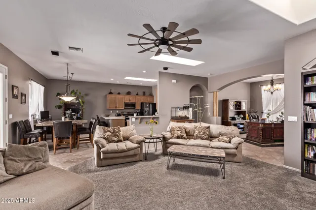 a living room with furniture a chandelier and a dining table with kitchen view