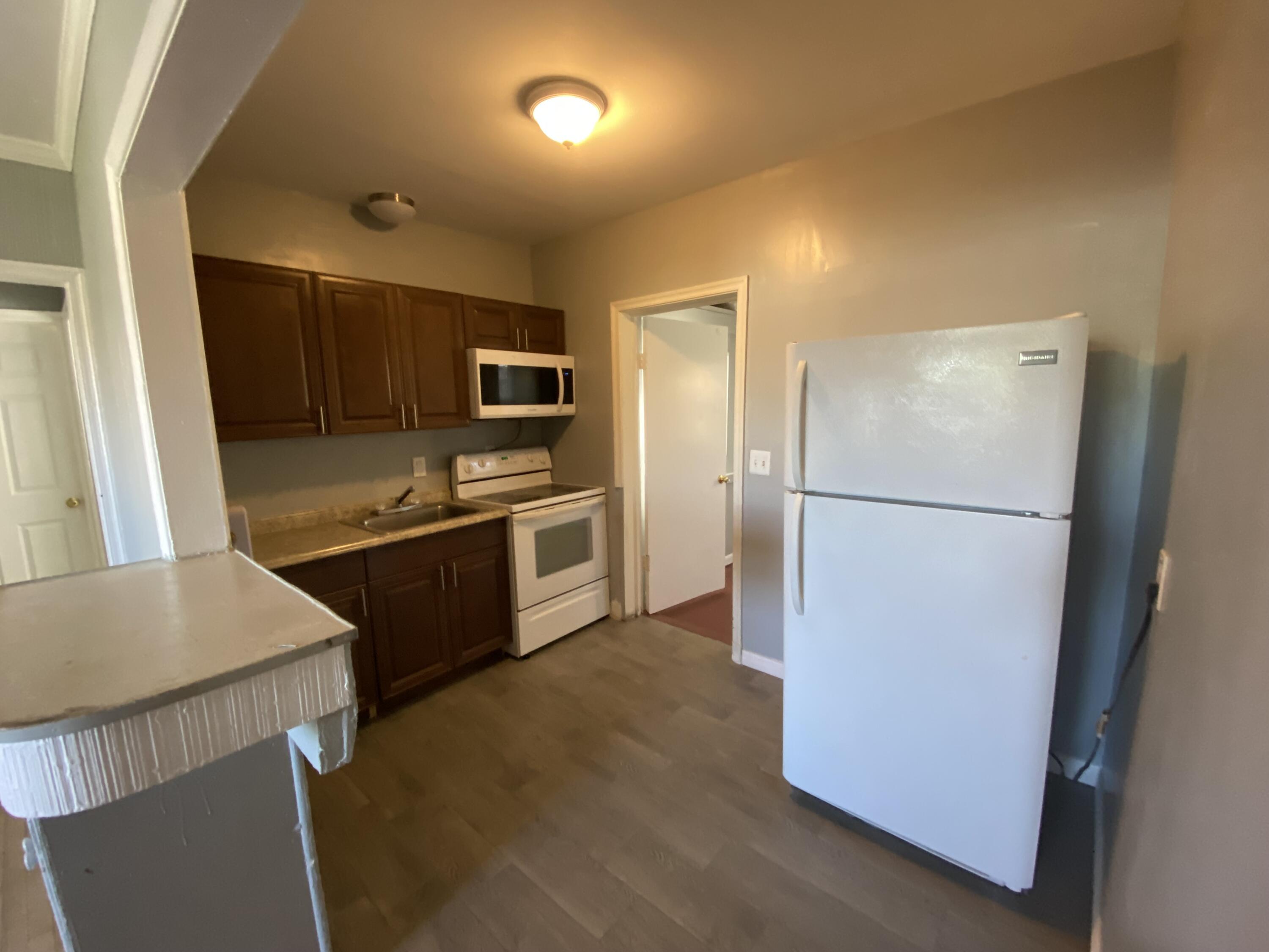 119 West 25th Street, Unit B Riviera Beach, FL 33404 - Photo 2 of 7 a kitchen with granite countertop a refrigerator and a sink