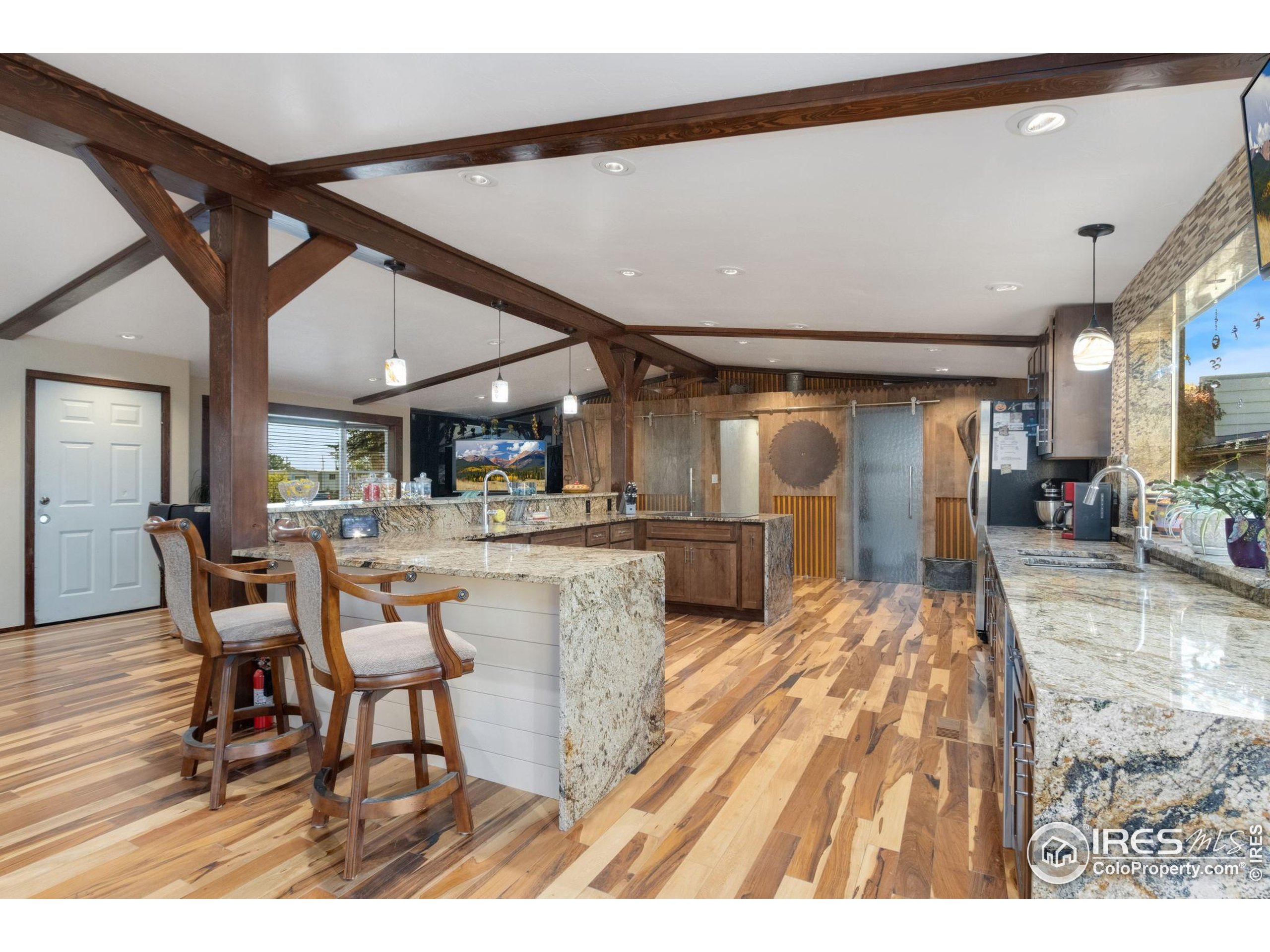 2801 Farview Drive Fort Collins, CO 80524 - Photo 12 of 40 a dining hall with stainless steel appliances kitchen island granite countertop a table chairs and a wooden floor