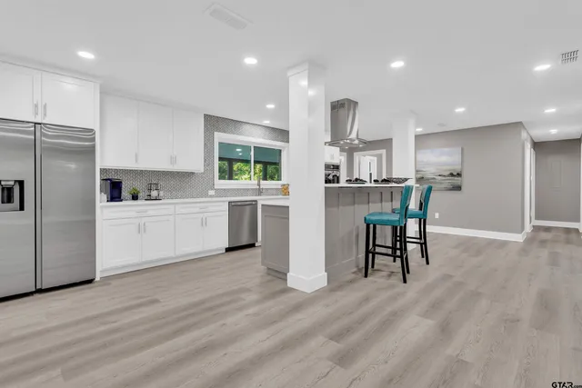 a kitchen with stainless steel appliances kitchen island granite countertop a refrigerator and a stove top oven