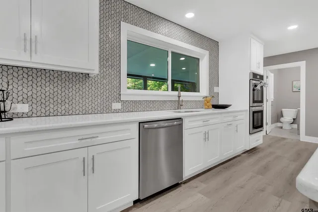 a kitchen with white cabinets and sink