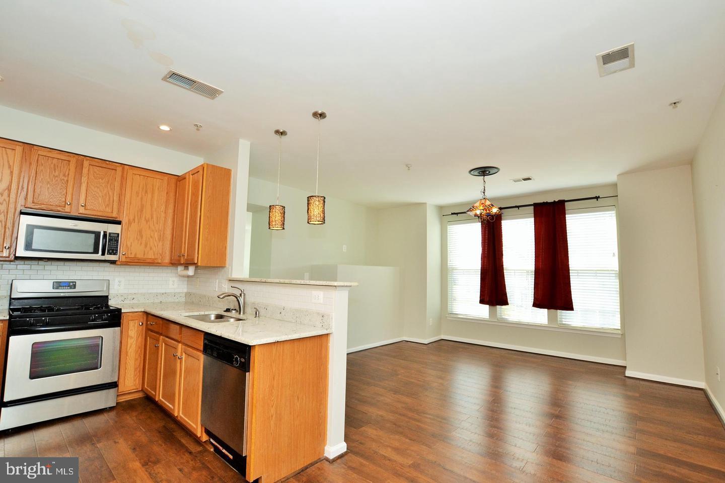 43048 Zander Terrace Ashburn, VA 20147 - Photo 18 of 18 a kitchen with stainless steel appliances kitchen island wooden cabinets and a window