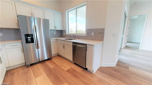 a view of a kitchen with wooden floor and electronic appliances