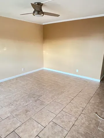 an empty room with a ceiling fan and carpet