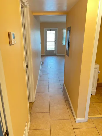 a view of a hallway with wooden floor and a bathroom