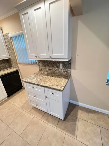 a view of kitchen with granite countertop white cabinets