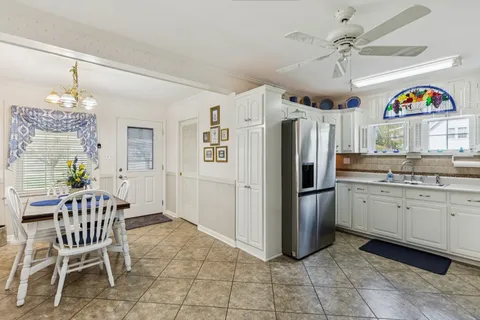 a kitchen with stainless steel appliances granite countertop a refrigerator a oven a sink a dining table and chairs with wooden floor