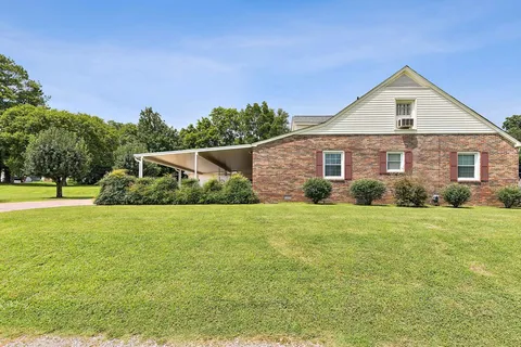 a front view of house with yard and trees in the background