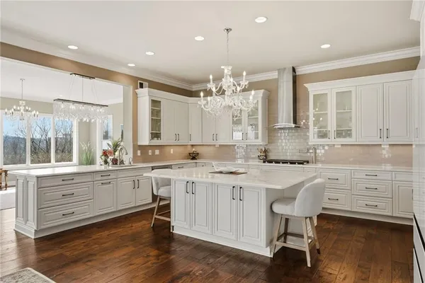 a large kitchen with cabinets a island and chairs in it