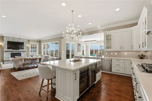 a kitchen with stainless steel appliances granite countertop a stove top oven a sink dishwasher a dining table and chairs with wooden floor