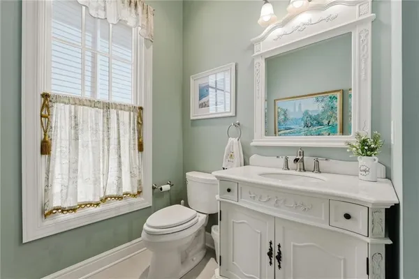 a bathroom with a granite countertop toilet a sink a mirror and a window