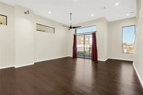 a view of an empty room with window and wooden floor