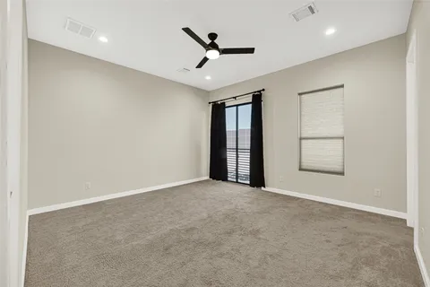 an empty room with ceiling fan and windows