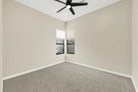 an empty room with windows and ceiling fan