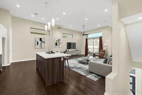 a large living room with stainless steel appliances granite countertop couches wooden floor and a kitchen view
