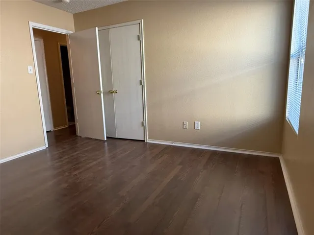 an empty room with wooden floor and window