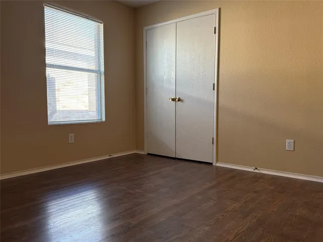 an empty room with wooden floor and window