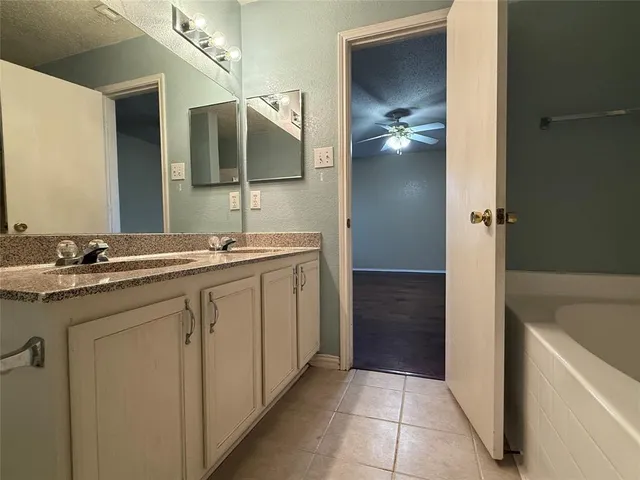 a en suite bathroom with a granite countertop sink and a mirror