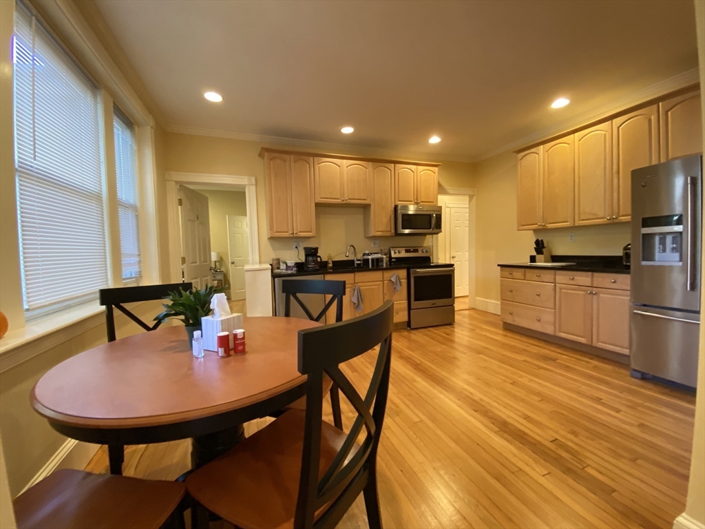 a kitchen with stainless steel appliances a dining table chairs refrigerator and sink