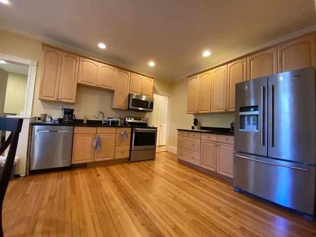 a kitchen with wooden floors stainless steel appliances and window