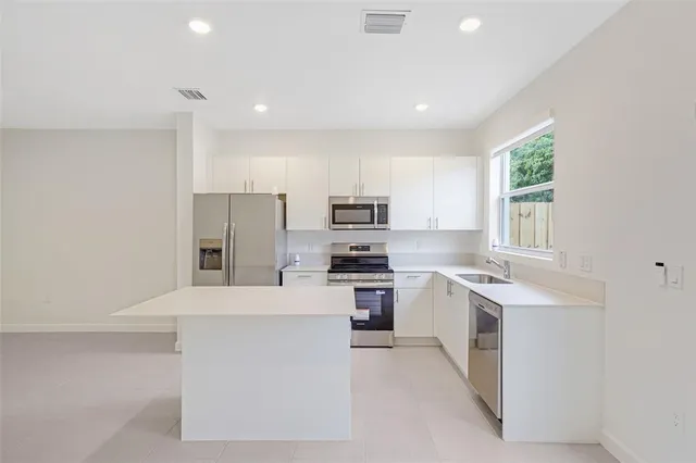 a large kitchen with stainless steel appliances granite countertop a stove a sink a refrigerator and a microwave