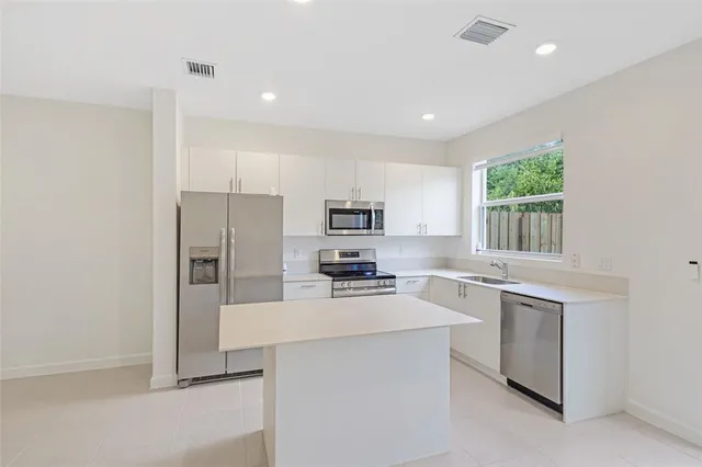 a kitchen with kitchen island granite countertop white cabinets and stainless steel appliances